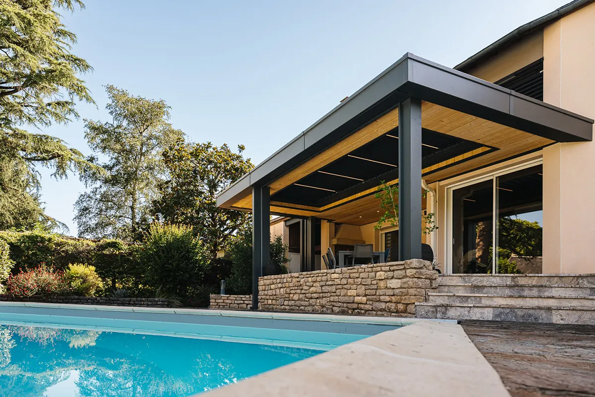 Pergola à toit plat avec lames bioclimatiques intégrées près d’une piscine à Espalion