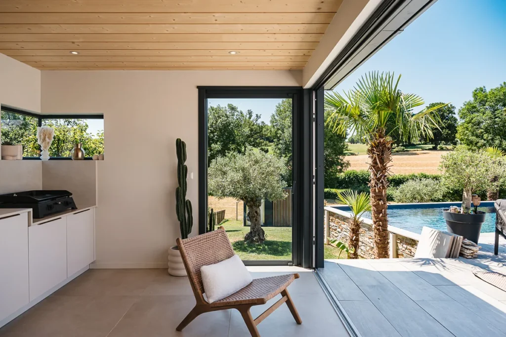 Intérieur lumineux d’un pool-house de 21 m² avec porte accordéon vitrée