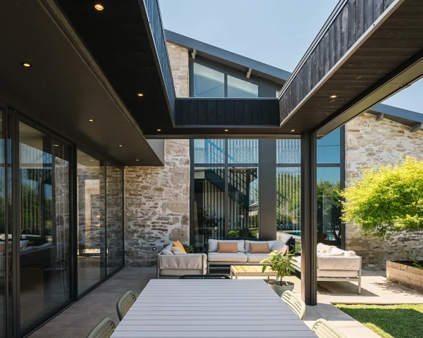 Terrasse couverte par une pergola sur mesure intégrée à une maison en pierre